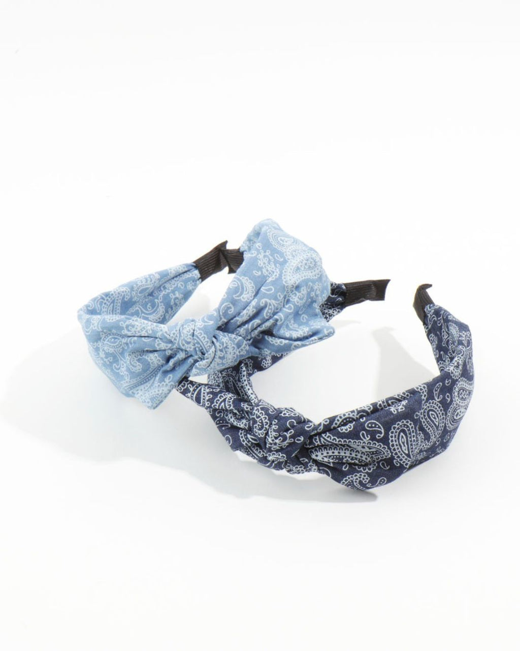 Two soft fabric knotted headbands in light blue and dark blue bandana prints overlapping on a bright white surface.