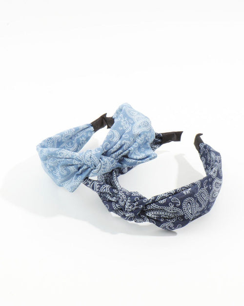 Two soft fabric knotted headbands in light blue and dark blue bandana prints overlapping on a bright white surface.