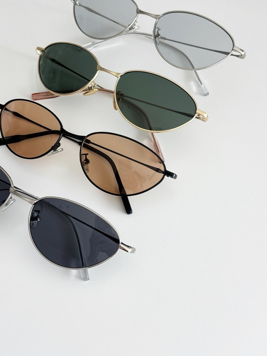 Four pairs of sunglasses with different lens colors and frames on a light gray background