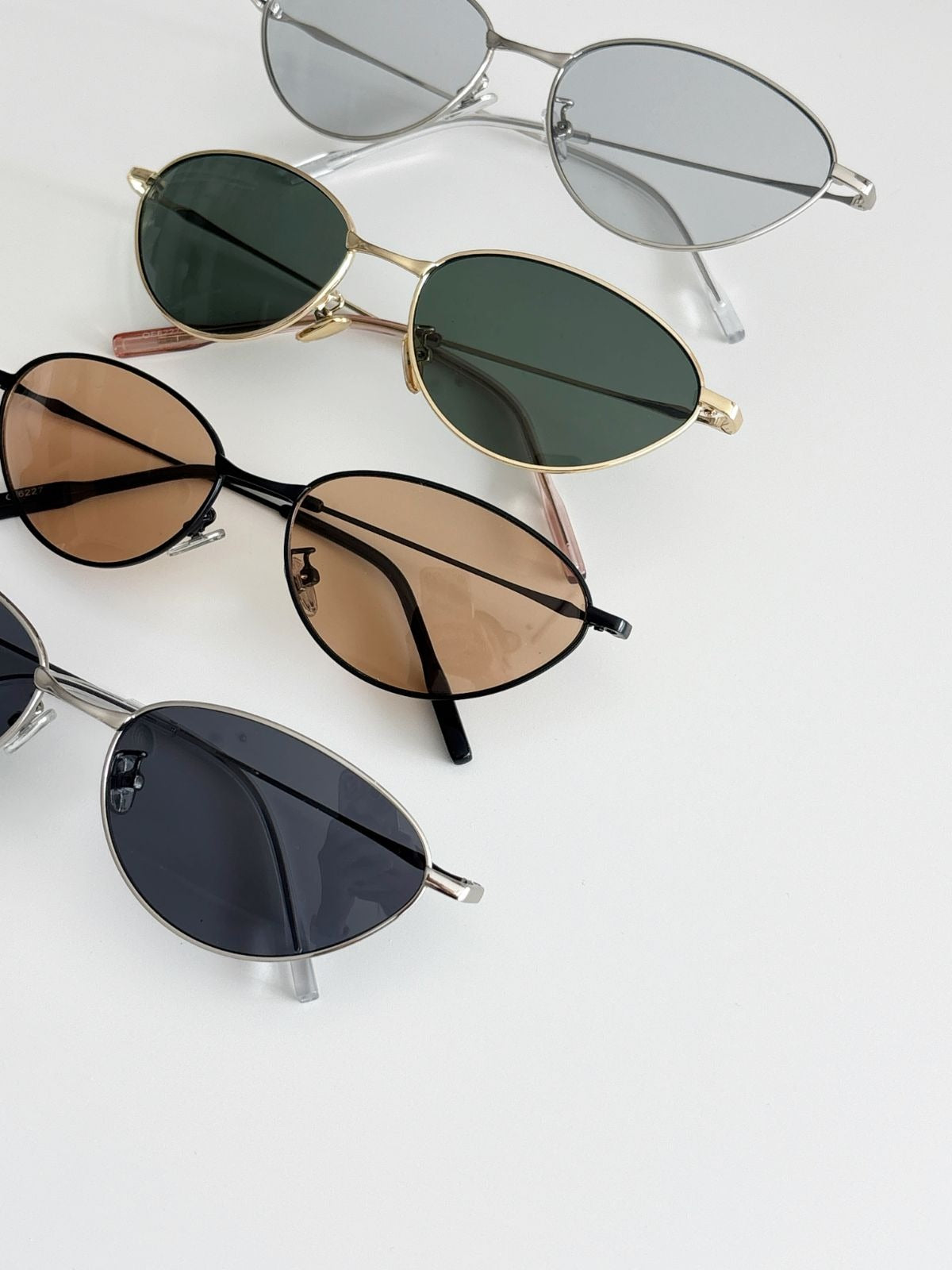 Four pairs of sunglasses with different lens colors and frames on a light gray background
