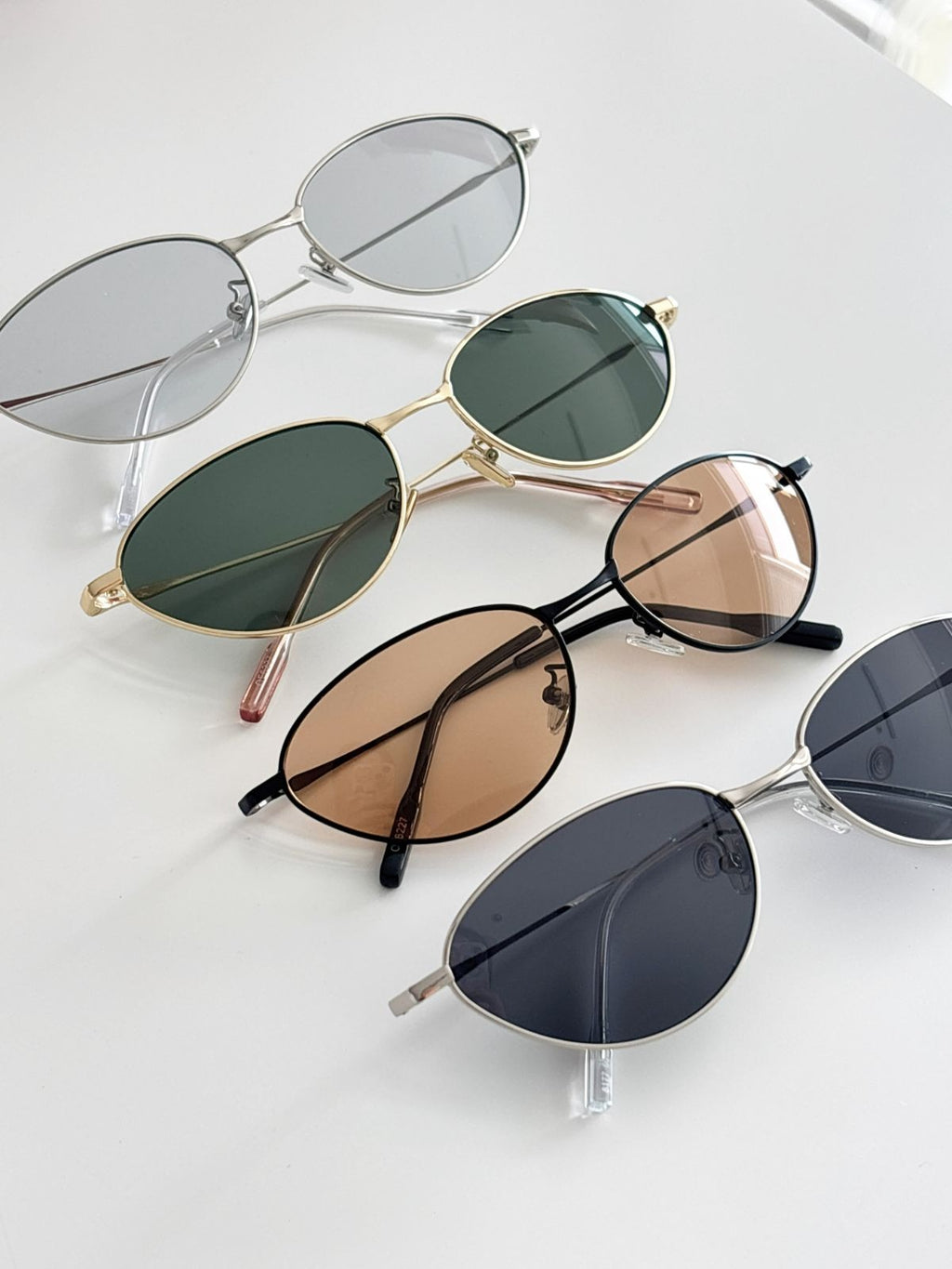 Set of oval-shaped sunglasses with different lens colors on a light gray background