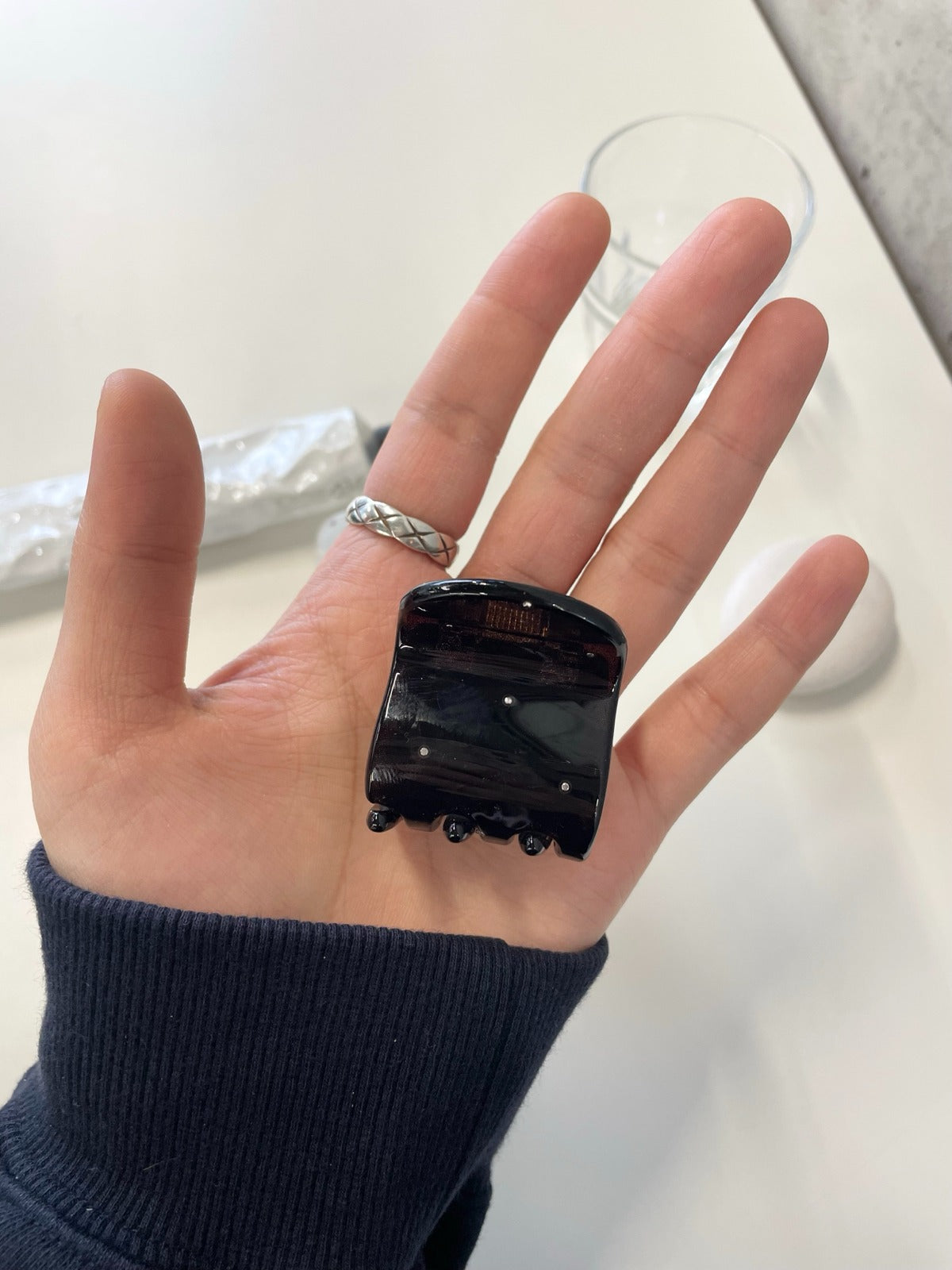 A dark tortoiseshell brown mini square hair claw clip featuring delicate silver rhinestone studs, resting in the palm of a hand.
