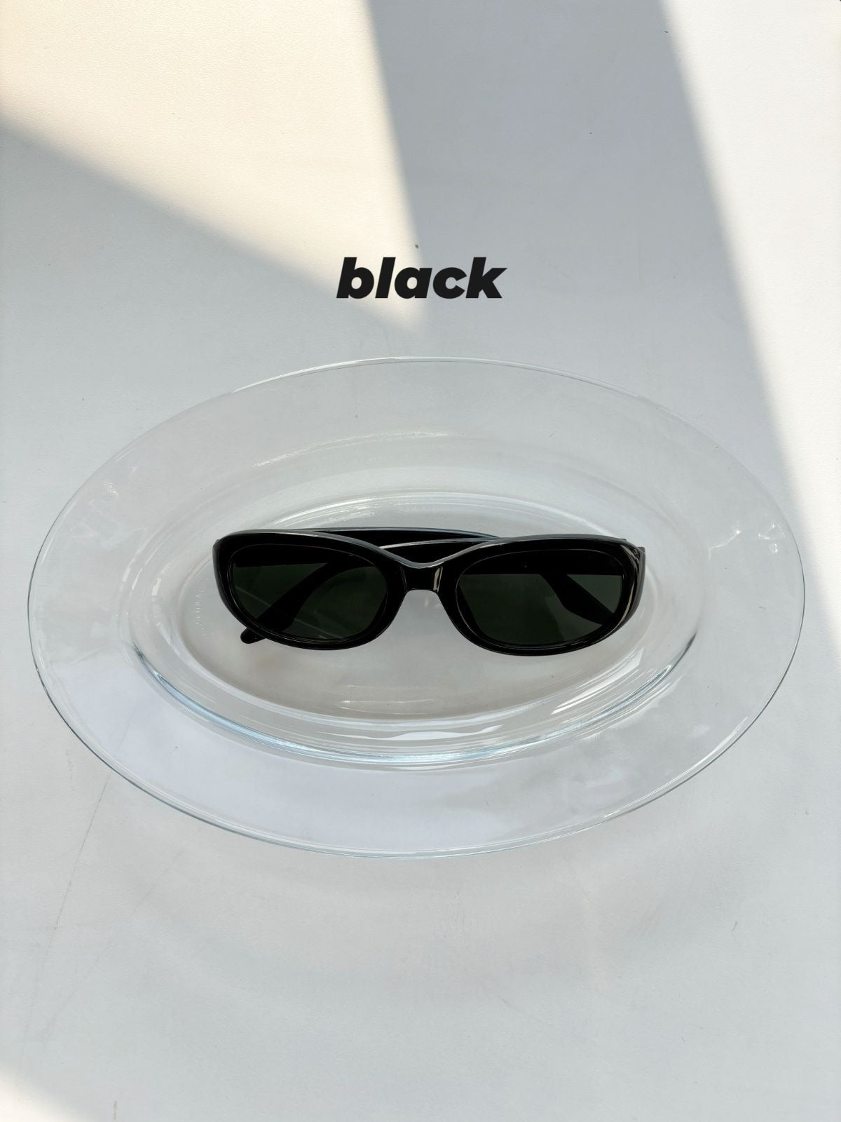 Black sunglasses on a clear stand with 'black' text above.