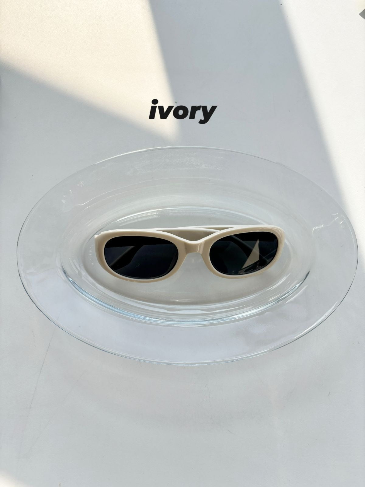Sunglasses on a clear stand with 'ivory' branding in the background