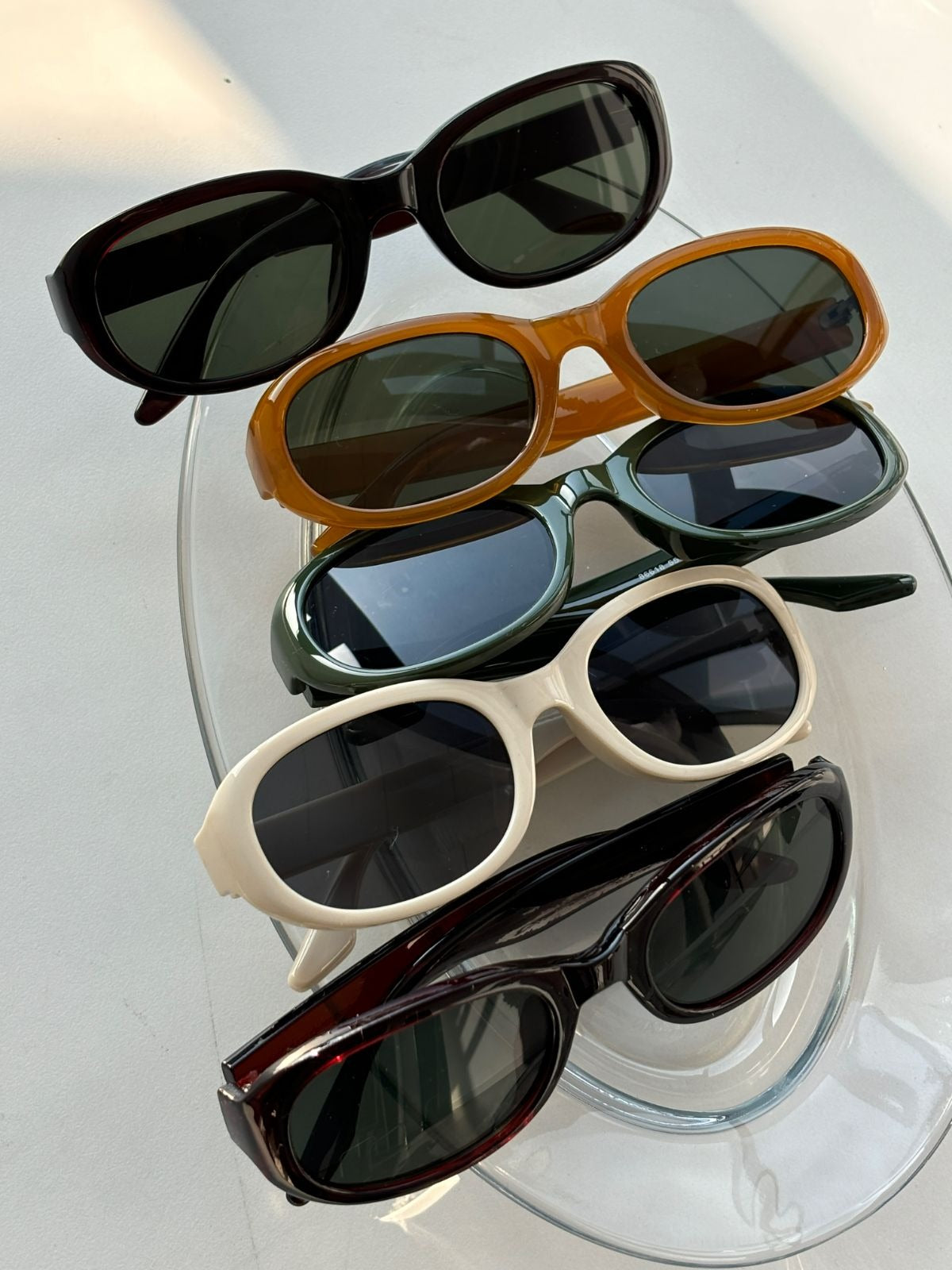 Collection of sunglasses on a clear stand with a white background
