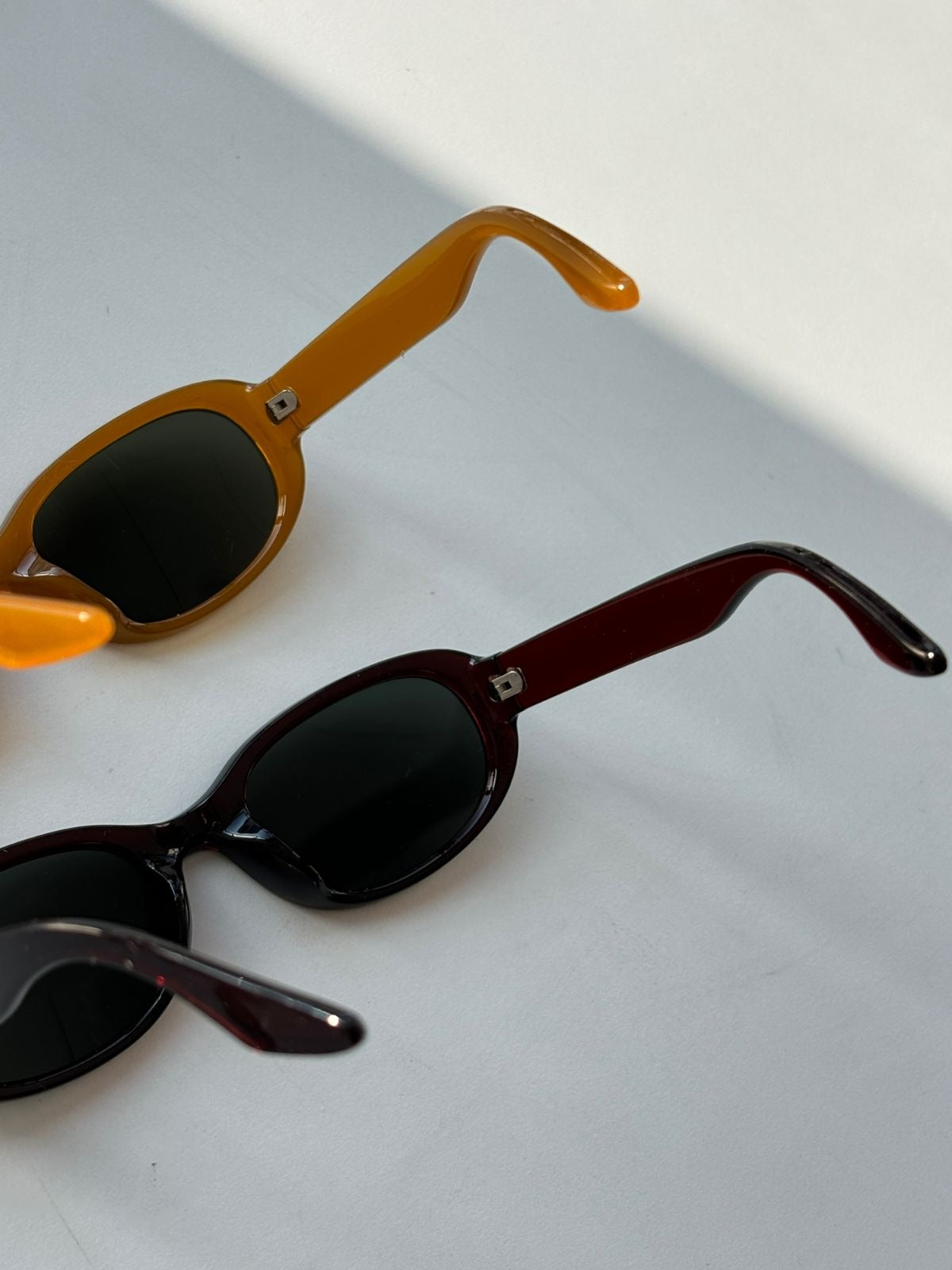 Two pairs of sunglasses with different frame colors on a light gray background