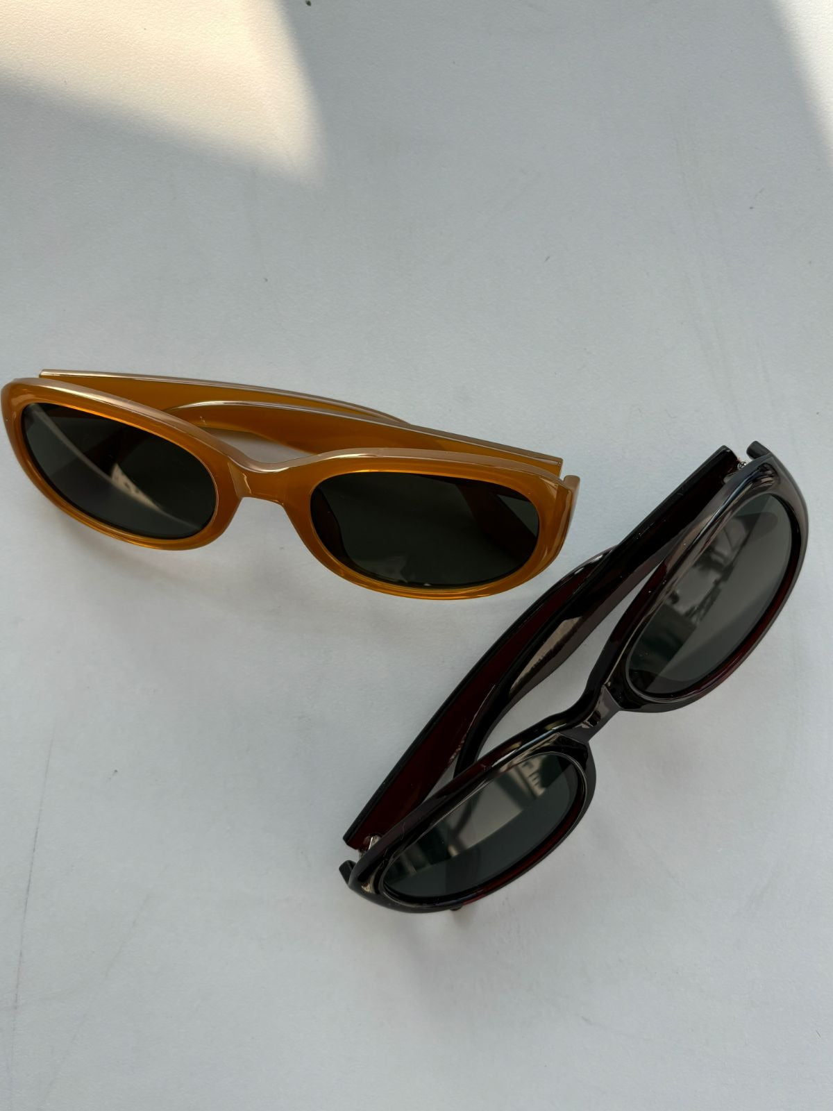 Two pairs of sunglasses, one brown and one black, on a white background.
