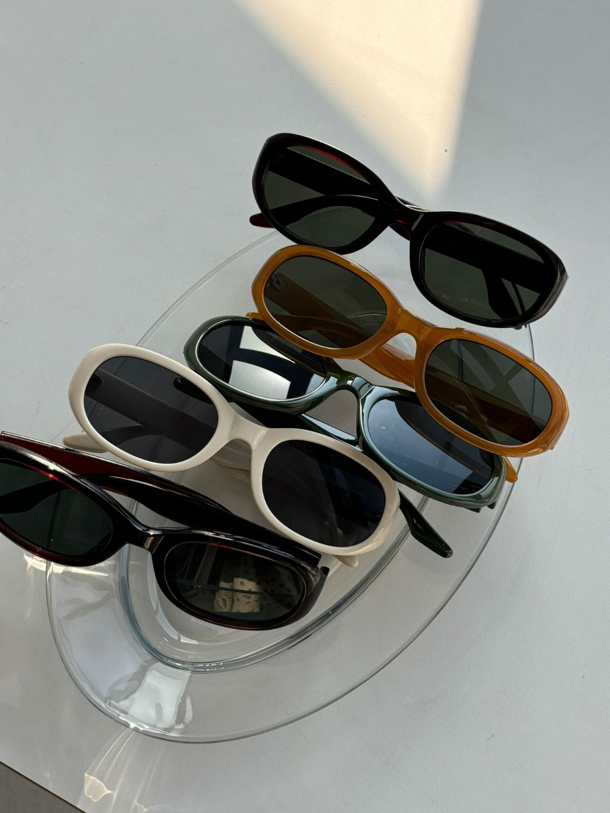 Set of sunglasses displayed on a clear stand against a light gray background